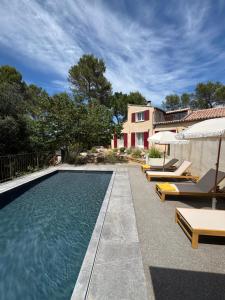 a swimming pool with lounge chairs and a house at Domaine d'Olga - Lodges & SPA in Aniane