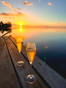 two glasses of wine sitting on a table with the sunset at Secret Spot Lagoon Dream in Moorea