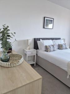 a bedroom with two beds and a table with a plant at River Breeze BALCONY 2 in Littlehampton