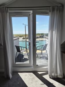 a sliding glass door with two chairs on a balcony at River Breeze BALCONY 2 in Littlehampton