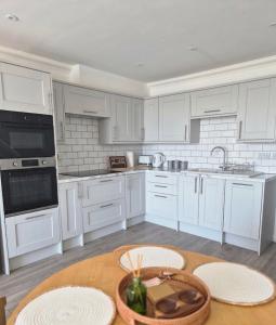 a kitchen with white cabinets and a wooden table at River Breeze BALCONY 2 in Littlehampton +8 photos