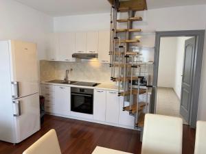 a kitchen with white cabinets and a spiral stair at Moro Crikva in Crikvenica
