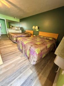 two beds in a room with green walls and wooden floors at Ranch House Motel in Marksville