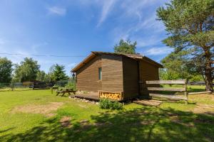 a small wooden house in a field with a bench at Pie lacuksa in Tīnūži