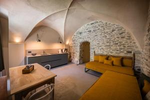 a living room with a yellow couch and a stone wall at Granuit Alpine Home in Sauze di Cesana