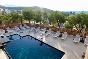 a swimming pool with white chairs and a swimming pool at Abelia Hotel in Ksamil