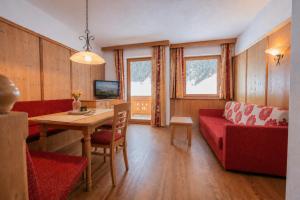 a living room with a red couch and a table at Alpenchalet Vital in Neustift im Stubaital