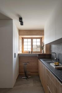 a kitchen with white cabinets and a sink and a stool at Le Chalet Remy in Saint-Gervais-les-Bains