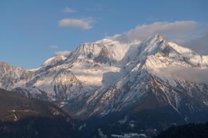 a mountain covered in snow and clouds in the sky at Le Chalet Remy in Saint-Gervais-les-Bains