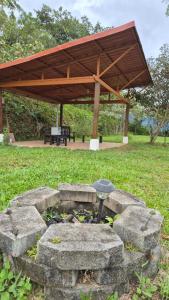 a stone fire pit in a park with a wooden roof at Cabaña Vista de Oro 2 in Paraíso