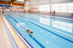 a woman swimming in an indoor swimming pool at Hotel CHODOV ASC in Prague +11 photos
