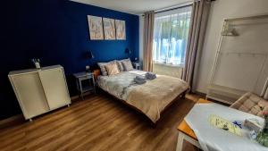 a bedroom with a bed and a blue wall at Apartamenty Nad Rzeką in Polanica-Zdrój