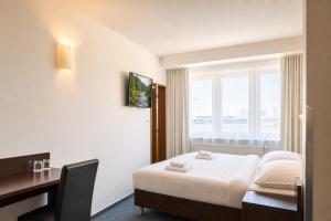 a room with a bed and a desk and a window at Hotel CHODOV ASC in Prague