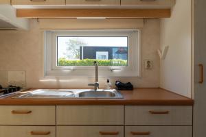 a kitchen with a sink and a window at chalet de kievit in Serooskerke +9 photos