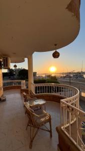 a balcony with chairs and the sunset in the background at luxor nile palace in Luxor