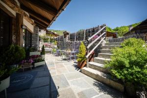 a patio with stairs and tables and potted plants at Granuit room & breakfast in Sauze di Cesana