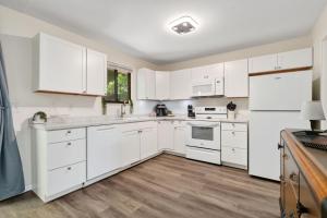 a white kitchen with white appliances and wooden floors at Backyard Hideaway with King Bed, Garage, Bicycles in Loveland