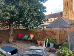 a patio with chairs and a tree and a fence at Divis street guest house in Belfast