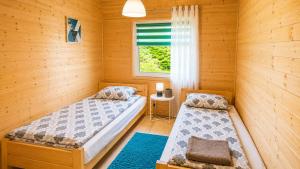 a bedroom with two beds and a window at Domki nad Soliną 665-189-444 OGRZEWANE in Solina