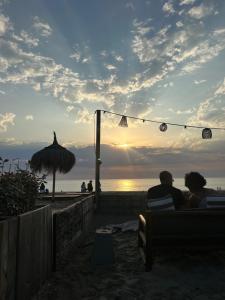 a couple sitting on a bench on the beach watching the sunset at Salty dunes in Noordwijk