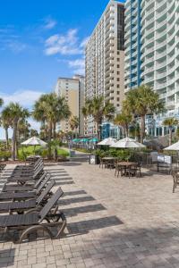 a row of benches and tables with trees and buildings at Breakers Resort Hotel in Myrtle Beach