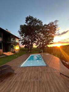 a swimming pool on a wooden deck with the sunset at Solar das Aroeiras in Serra do Cipo