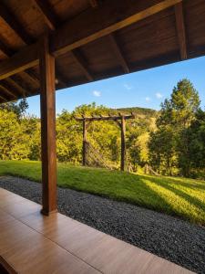 a porch with a view of a field and a fence at Refúgio Rural Ipê Lago e Fogueira ao Ar Livre in Campo Alegre