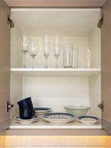 a shelf with wine glasses and plates and bowls at Refúgio Rural Ipê Lago e Fogueira ao Ar Livre in Campo Alegre +20 photos