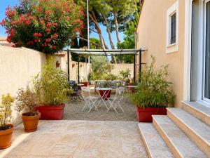 a patio with a table and chairs and flowers at Lou Meinado, un concept "comme à l'hôtel" in Saint-Martin-de-Crau