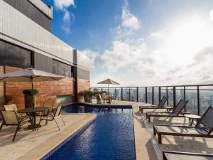 a pool on top of a building with chairs and tables at Flats no coração de Belém in Belém