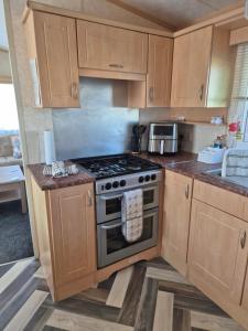 a kitchen with wooden cabinets and a stove top oven at Mark and Teresa's 8 berth caravan on Coral Beach Ingoldmels in Ingoldmells