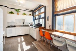 a kitchen with white cabinets and orange chairs at The Guesthouse Vancouver Downtown in Vancouver