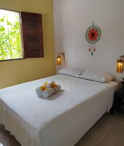 a white bed with two stuffed animals sitting on it at Villa of the Palm Trees in Icaraí +23 photos