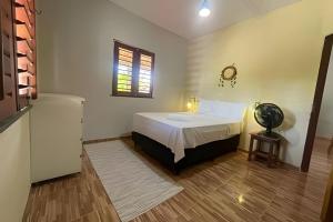 a bedroom with a bed and a window and a fan at Villa of the Palm Trees in Icaraí