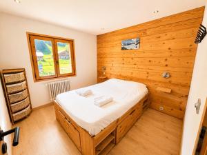 a bedroom with a bed with a wooden wall at *** Le Refuge *** Logement standing Megève in Demi-Quartier