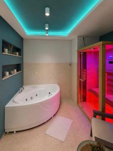 a large white tub in a bathroom with pink lighting at Apartman Spa Bačka in Bačka Palanka +25 photos