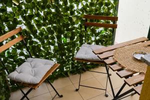 two chairs and a table in front of a green hedge at Apartman Spa Bačka in Bačka Palanka