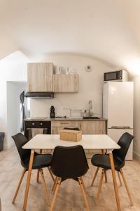 a kitchen with a table and chairs and a refrigerator at Le Loft in Sainte Anastasie - Aubarne