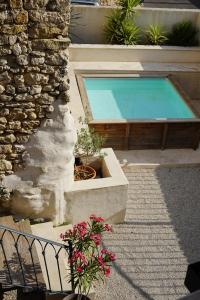 a swimming pool next to a stone building with flowers at Le Loft in Sainte Anastasie - Aubarne