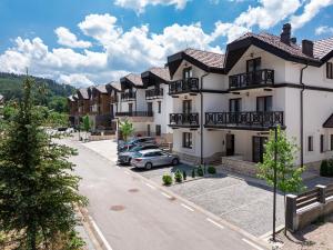 a row of houses with cars parked in a parking lot at MonteBreza Spa Apartment Jacuzzi, Sauna & Free Parking in Kolašin