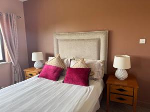 a bedroom with a white bed with pink pillows at The Country Haven Aircode V31Y166 in Ballybunion