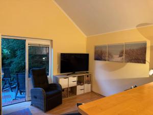 a living room with a television and a chair at Ferienhaus Loubier Marne in Marne
