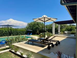 a patio with a table and an umbrella next to a pool at V Mira Luxury Villa in Tragaki