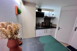 a kitchen with a table and a vase with a plant at Etablissement Cloutiers comprenant plusieurs logements de type studio - Hyper Centre Brive in Brive-la-Gaillarde