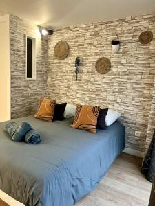 a large bed in a room with a brick wall at Etablissement Cloutiers comprenant plusieurs logements de type studio - Hyper Centre Brive in Brive-la-Gaillarde +19 photos