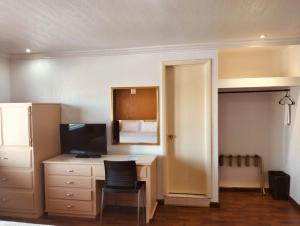 a bedroom with a desk with a television and a bed at Hotel Regis in Mexicali