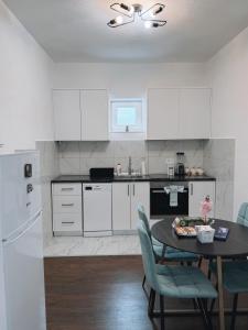a kitchen with white cabinets and a table with chairs at M&M Trebinje in Trebinje