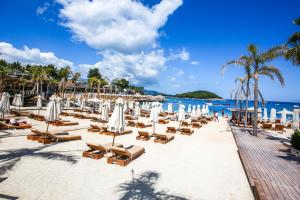 a beach with lounge chairs and umbrellas and the ocean at King Hotel Ksamil in Ksamil