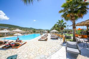 a resort with a pool with lounge chairs and palm trees at Hotel Lake Park Ksamil in Ksamil