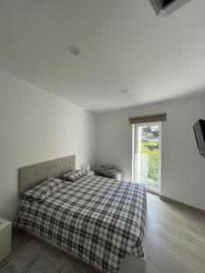 a white bedroom with a bed and a window at Figueira River House in Bragança